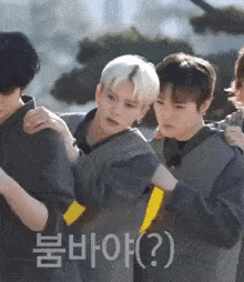 a group of young men are standing next to each other and one of them is holding another man 's arm .