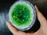 a person holding a crocheted object with green beads