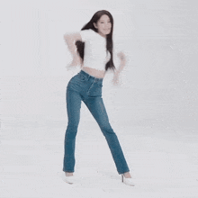 a woman in a white shirt and blue jeans is dancing in a white room .