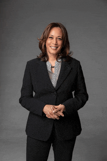 a woman wearing a black suit and a white shirt smiles for the camera