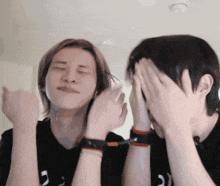 two people covering their faces with their hands and one has the letter c on his sleeve