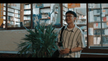 a man in a striped shirt stands in front of a bookstore holding a glass