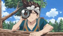 a boy in a blue shirt is looking through a camera