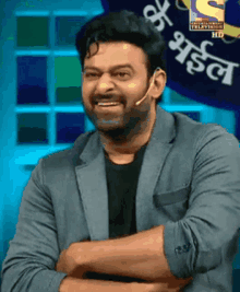 a man in a suit is smiling with his arms crossed in front of a sign that says entertainment