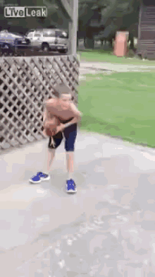 a young boy is playing basketball on a sidewalk with a live leak watermark