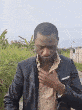 a man in a suit adjusts his jacket while standing on a dirt road