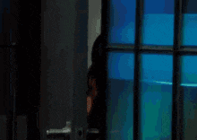 a woman is standing in front of a window with blue lights .