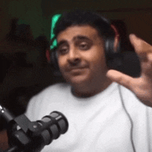 a man wearing headphones is sitting in front of a microphone and waving .