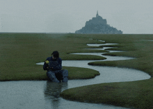 a person sits in a puddle of water in a field