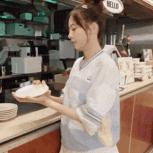 a woman holding a plate in front of a sign that says " hello "