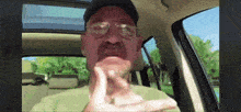 a man wearing glasses and a hat is sitting in a car