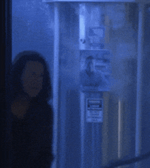 a woman with long hair is standing in a dark room with a blue background