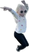 a little girl wearing sunglasses and a white shirt with flowers on it is jumping in the air