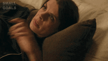 a woman is laying on a bed with small achievable goals written on the bottom