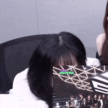 a woman is sitting in front of a screen with the word show on it
