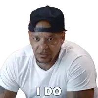a man wearing a baseball cap and a white shirt says i do