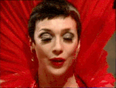 a close up of a woman 's face wearing a red dress and a red fan .