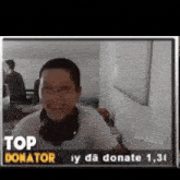 a man wearing headphones is sitting in front of a screen that says top donator .