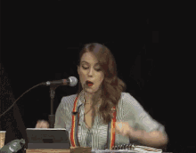 a woman is singing into a microphone while sitting at a table