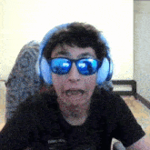 a young man wearing headphones and sunglasses is making a face .