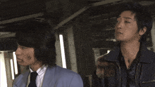 a man in a suit and tie is standing next to another man in a jacket