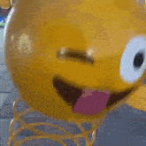 a yellow smiley face with a pink tongue sticking out is sitting on a spring .