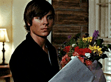 a young man holding a bouquet of flowers and a piece of paper