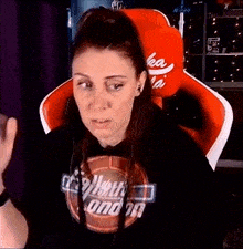 a woman is sitting in a red and white chair wearing a black hoodie .