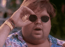 a fat man wearing sunglasses is looking through his glasses