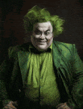 a man with green hair and glasses is wearing a green jacket and shirt