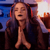 a woman with blue hair wearing headphones praying