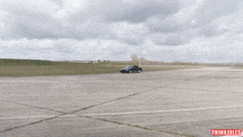 a black car is driving on a concrete road with thinkjules written on the bottom left