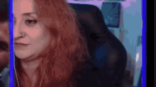 a woman with red hair is sitting in a chair in front of a blue screen