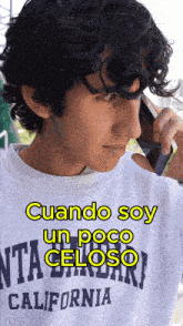 a man wearing a california shirt is talking on his cell phone