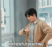 a man is looking at his watch with the words patiently waiting behind him