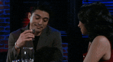 a man and a woman are sitting at a table drinking wine