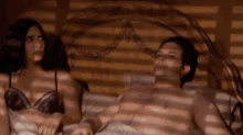 a man and a woman are laying on a bed and the man is saying " i 'm not denying it "