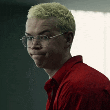 a man wearing glasses and a red shirt makes a face