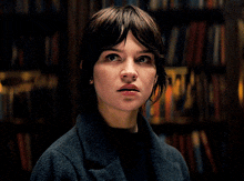 a close up of a woman 's face with books in the background