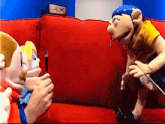 two stuffed animals are sitting on a red couch and one of them has a pac man sign on the wall behind them