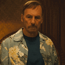 a man wearing a blue shirt and a hawaiian shirt