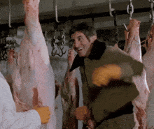 a man in a green jacket is standing in front of a bunch of meat