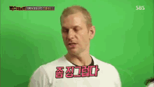 a man in a white shirt is talking in front of a green screen with sbs written on it .