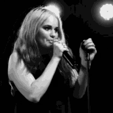 a woman singing into a microphone on a stage in a black and white photo