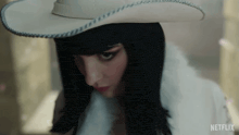 a close up of a woman wearing a white hat and a white coat .