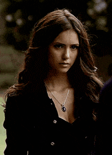 a woman wearing a necklace and a black jacket