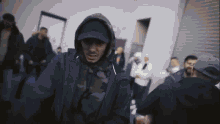 a man in a hooded jacket stands in a crowd of people