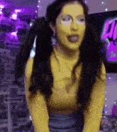 a woman wearing a yellow shirt and pigtails is sticking out her tongue .