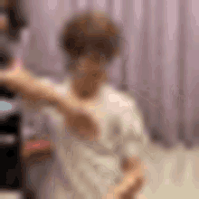 a blurry picture of a person standing in front of a purple curtain in a room .