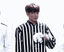 a man wearing a black and white striped shirt is holding a stuffed animal in his hand .